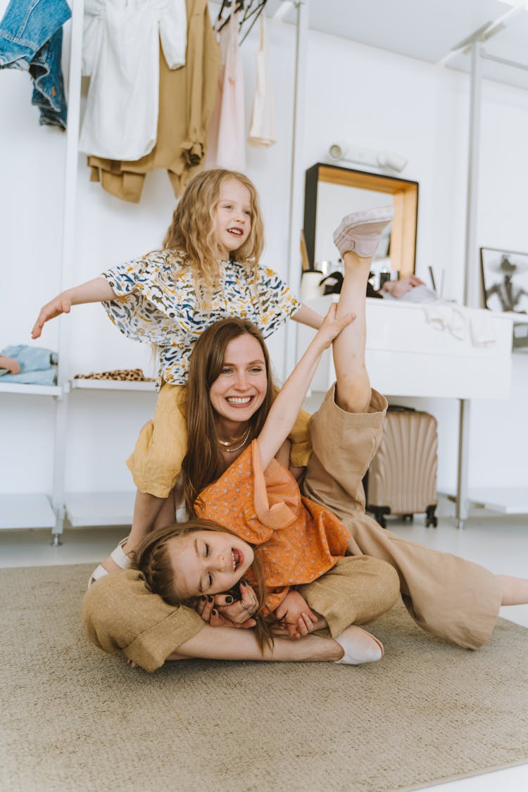 A Women With Cute Girls Playing Over The Carpet