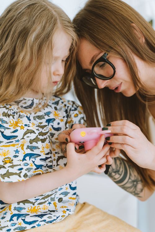 Free A mother and daughter are interacting with a toy camera, fostering learning indoors. Stock Photo