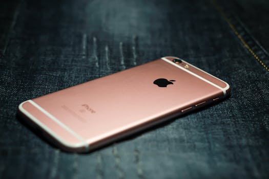 Close-up of a rose gold smartphone placed on dark denim fabric, highlighting tech style.
