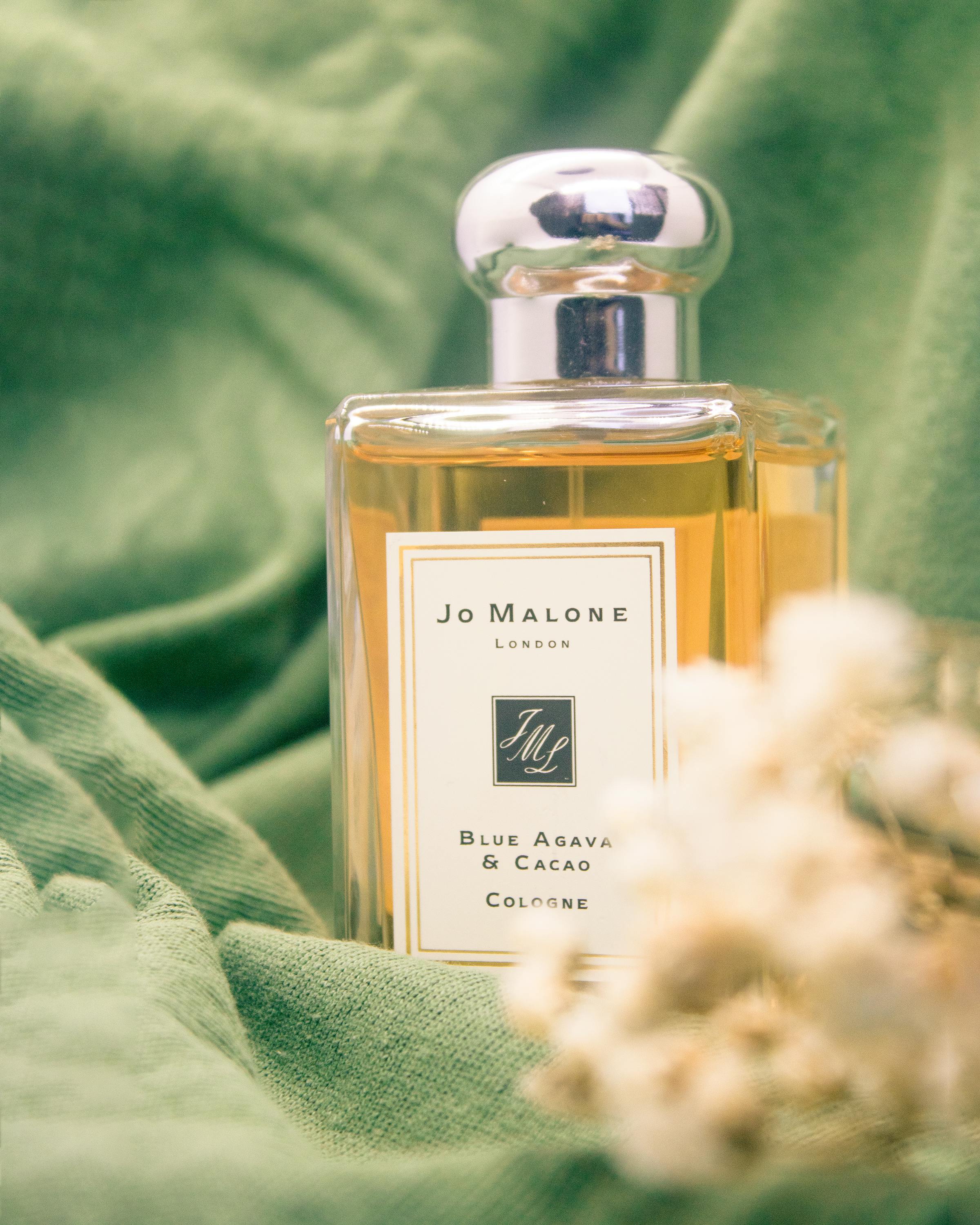 A luxurious Jo Malone perfume bottle styled on soft green fabric for an elegant still life shot.