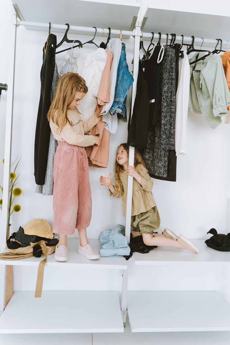 Girls Playing On The Cabinet With Hanging Clothes 