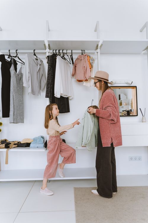 Free A mother and daughter enjoy a bonding moment while choosing outfits in a stylish modern closet. Stock Photo
