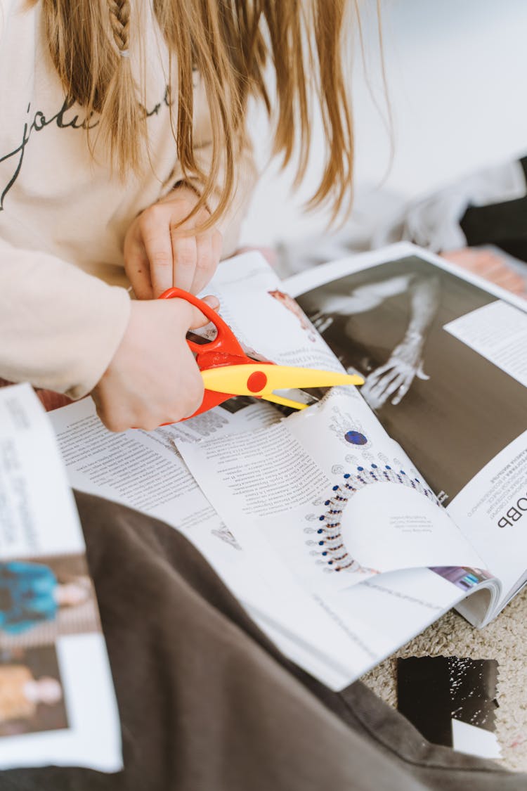 A Person Cutting The Pages Of A Magazine