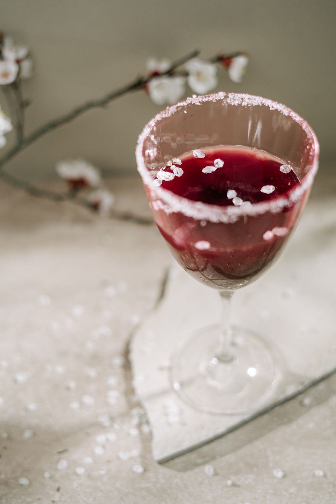 Blossom branch beside a sugar-rimmed coupe of sakura spritz on linen — photo by Ivan S on Pexels