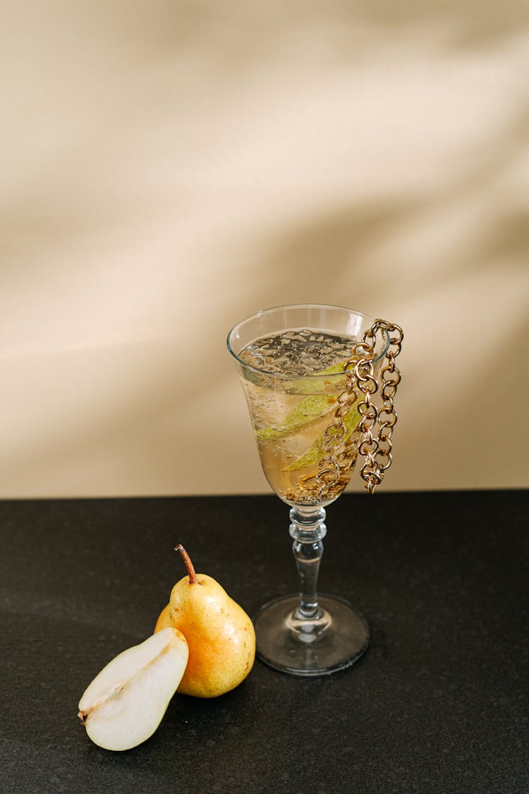 A Glass Of Drink With Sliced Fruit And Chain