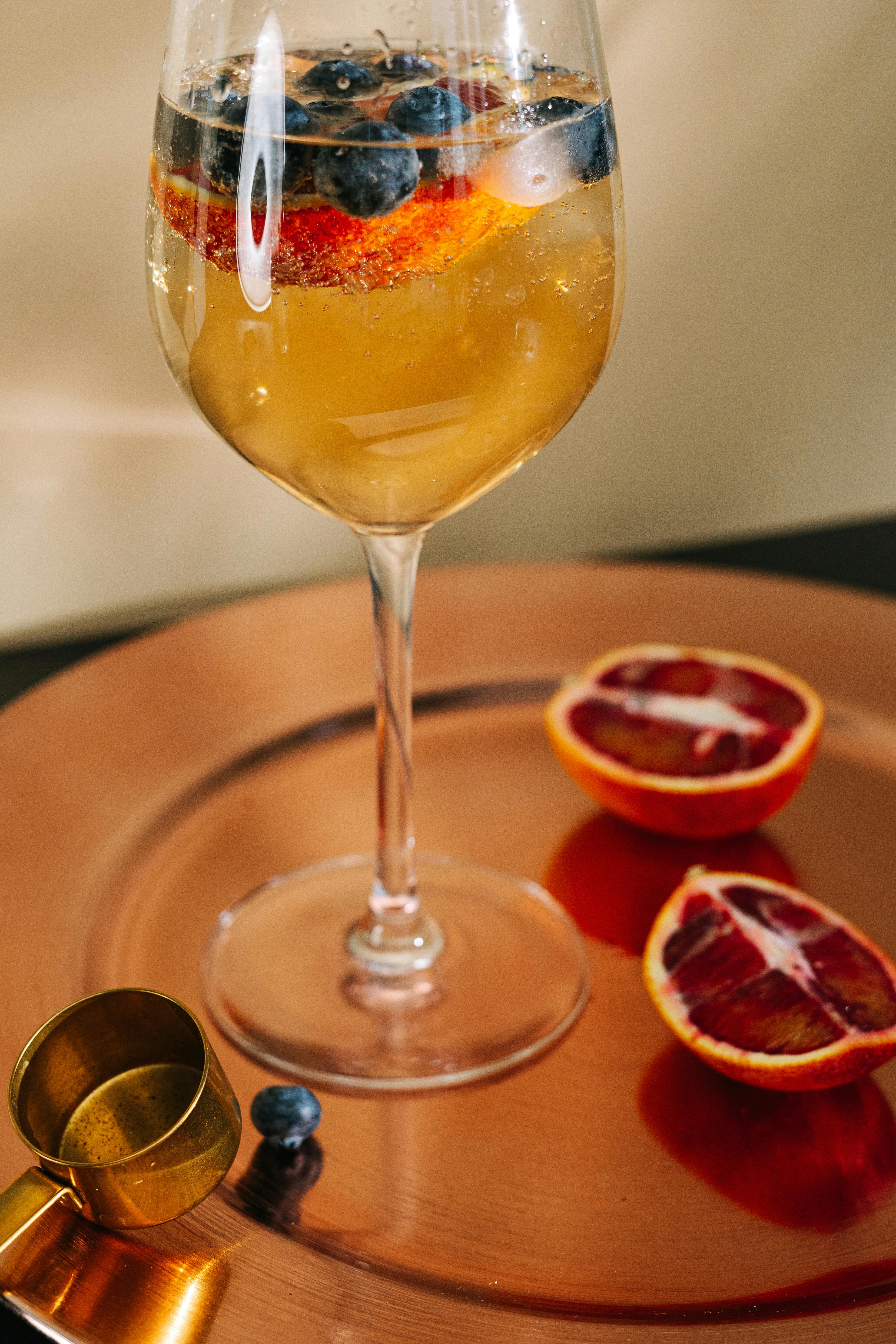 Elegant cocktail with orange and blueberry garnish on a copper platter. Perfect for a sophisticated setting.