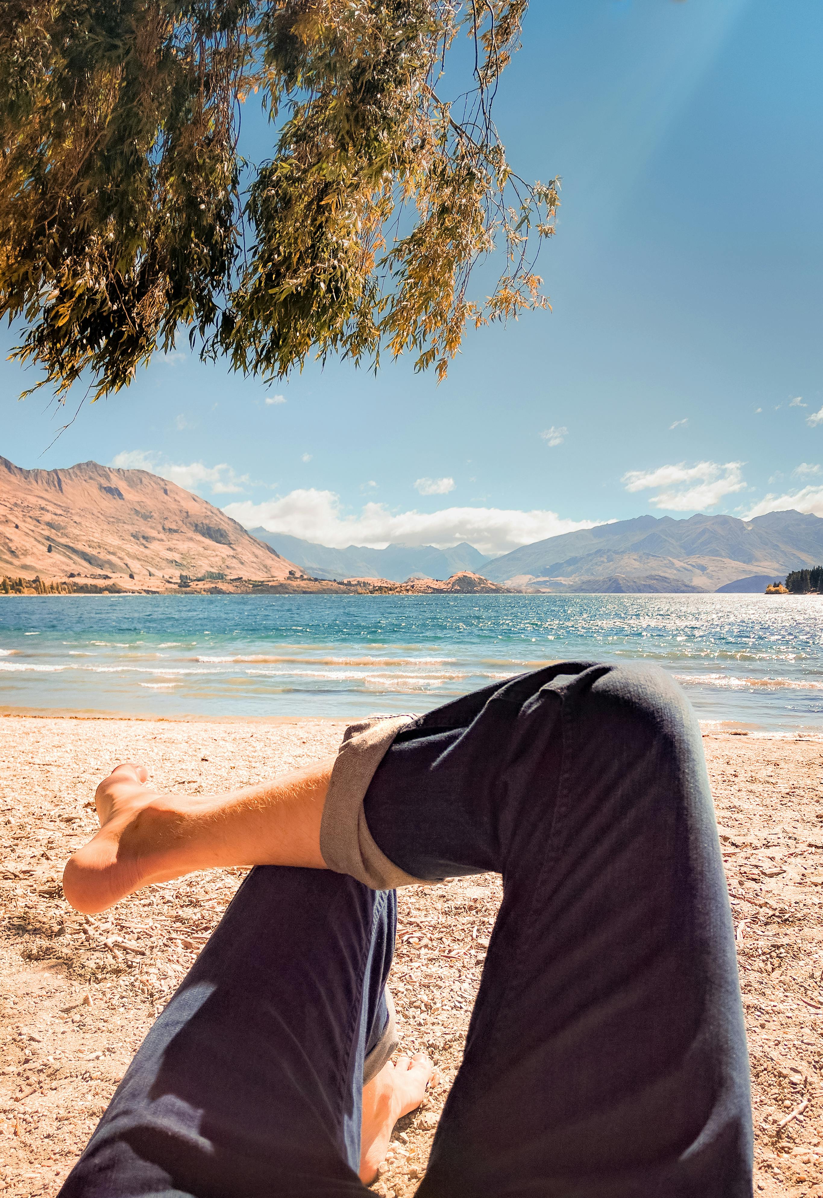 person wearing blue jeans laying on beach