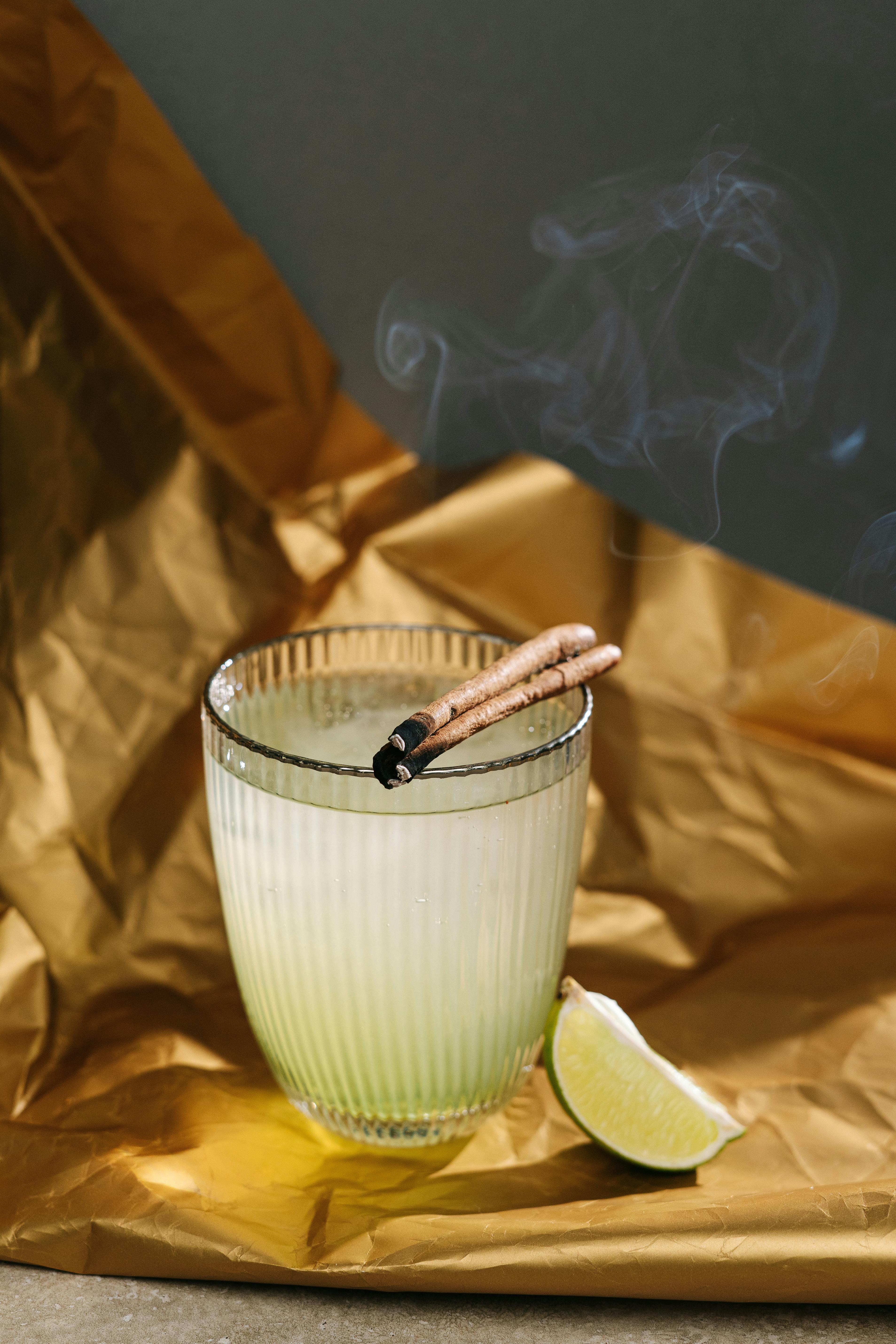 Lime Juice in a Glass with burning Cinnamon Sticks · Free Stock Photo