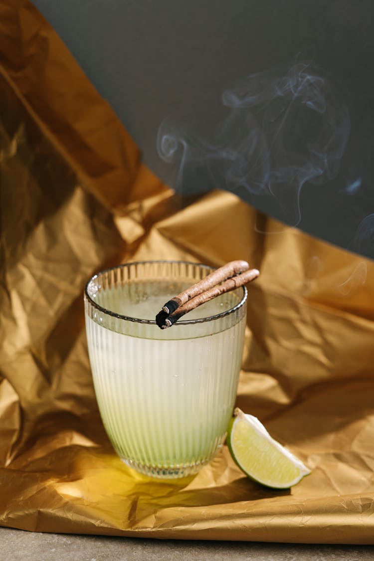 Lime Juice In A Glass With Burning Cinnamon Sticks