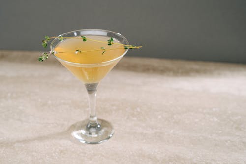 Twigs on Yellow Drink in Cocktail Glass