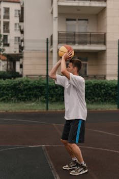 Young caucasian man playing basketball outdoors in an urban setting, capturing a dynamic shot.