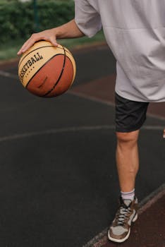 Man dribbling a basketball on an outdoor court. Action shot capturing the motion and dynamics of the sport.
