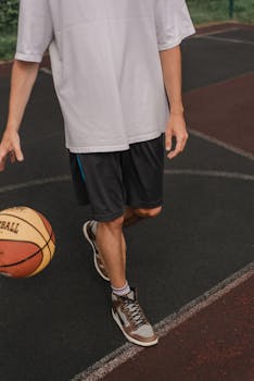 Adult man dribbles a basketball on an outdoor court, showcasing focus and determination.