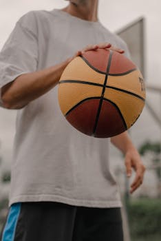 A man holds a basketball in an outdoor setting, capturing the essence of the sport.