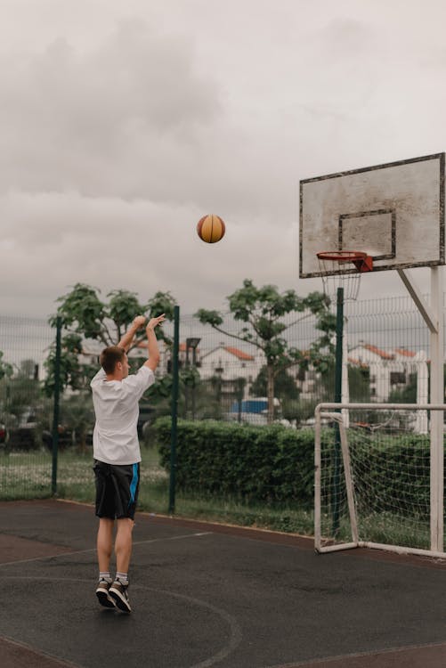 Free Person in White Shirt Shooting a Ball Stock Photo