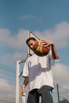 Caucasian man playing basketball outdoors on a sunny day.