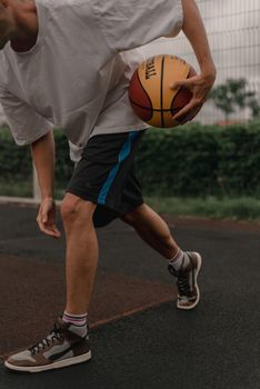 Close-up of a young man practicing basketball dribbling on an outdoor court.