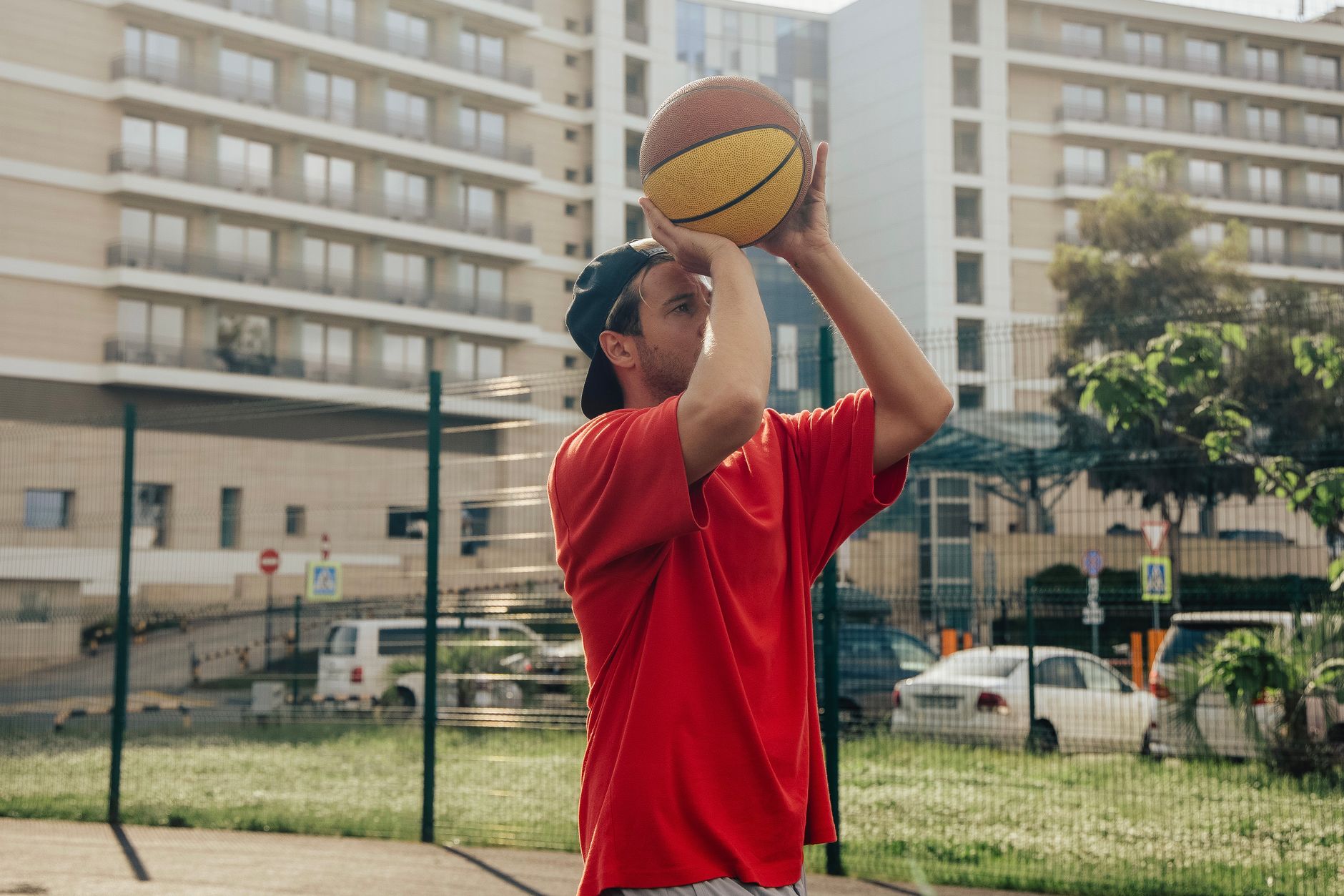 A young basketball player practicing low dribbles on an outdoor court at sunset