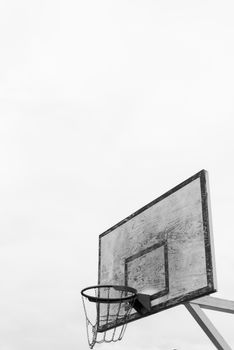 A minimalist view of an outdoor basketball hoop against a bright sky, capturing the essence of the sport.