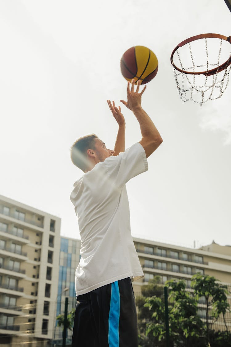 A Man Shooting A Basketball To The Hoop