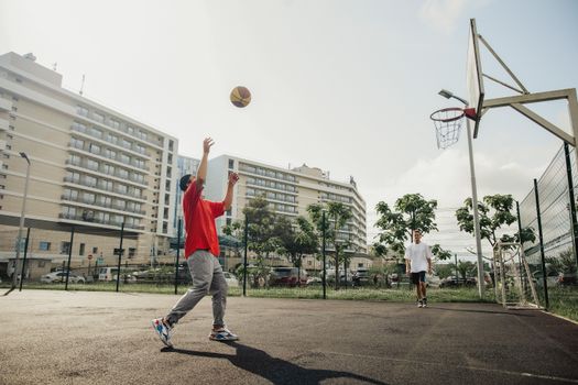 Two men playing basketball on an outdoor court in an urban area.