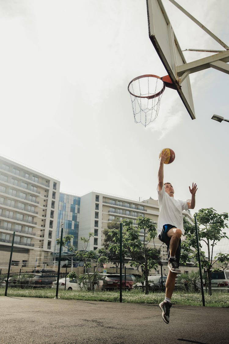 A Man Shooting A Basketball Doing A Layup