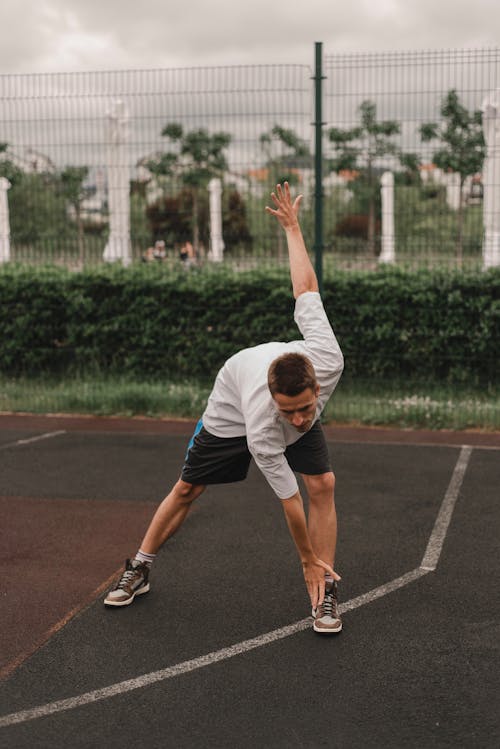 Free A Man Doing Stretching Exercise in a Basketball Court Stock Photo