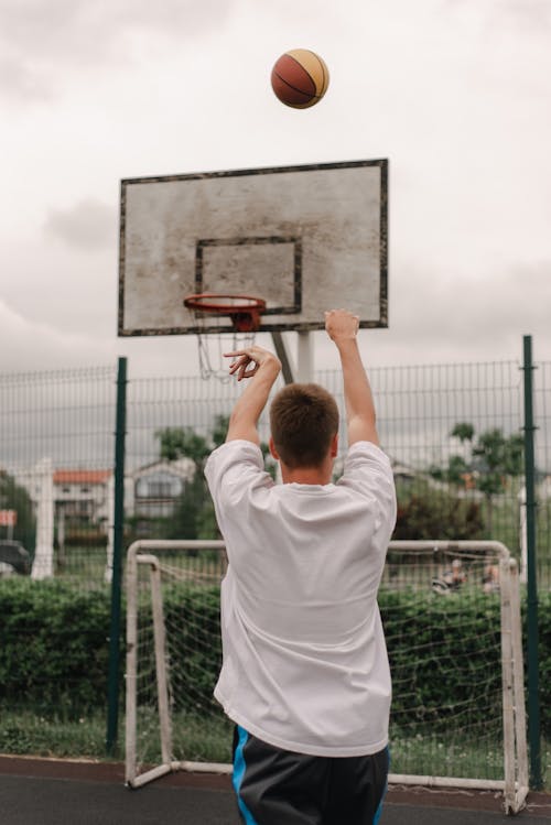 Man in White T-shirt Holding Red and Gray Basketball Hoop