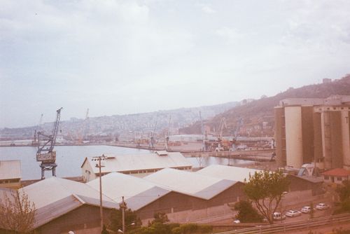 Free A coastal industrial area with cranes and buildings under a cloudy sky. Stock Photo