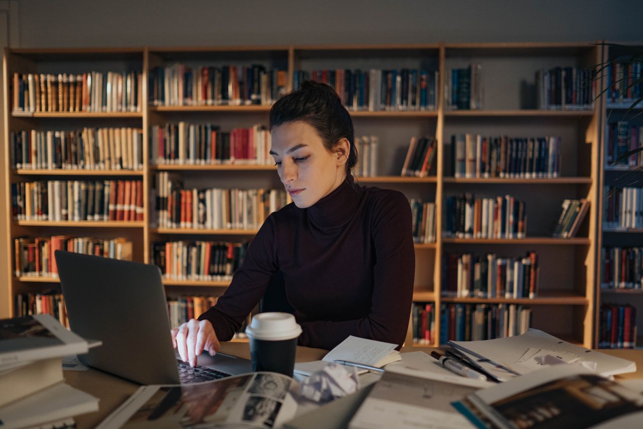 Adult woman intensely focused while working on a laptop in a library setting