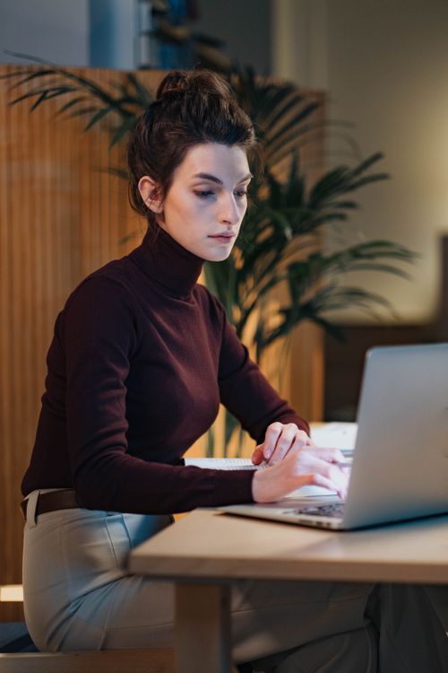 Free Confident woman using laptop in a stylish office setting. Perfect for business and technology themes. Stock Photo