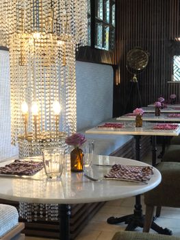 Stylish restaurant in Ubud with crystal chandelier and chic table setting, offering a warm and inviting dining atmosphere.