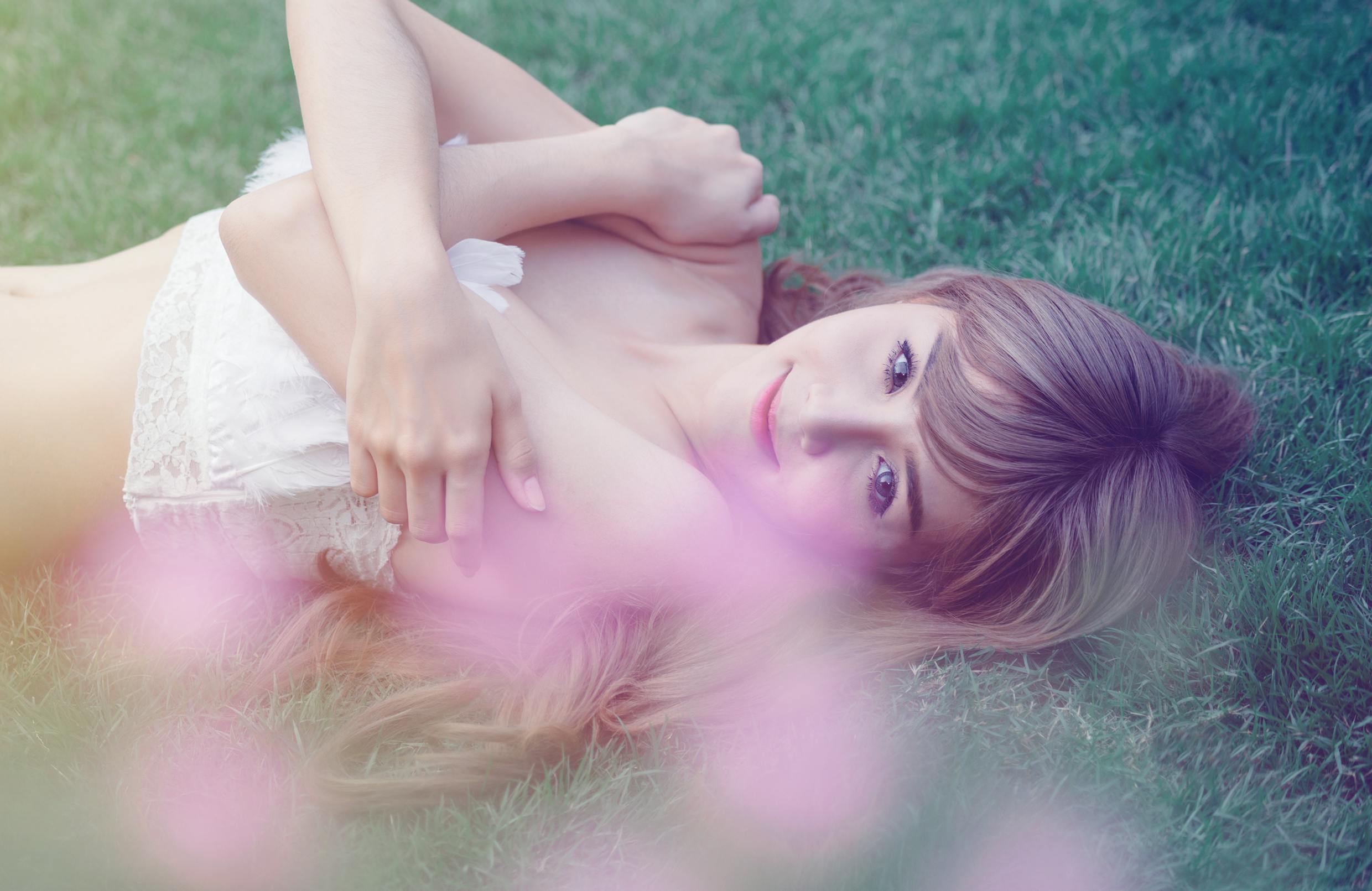 photo of a woman lying on green wearing white top