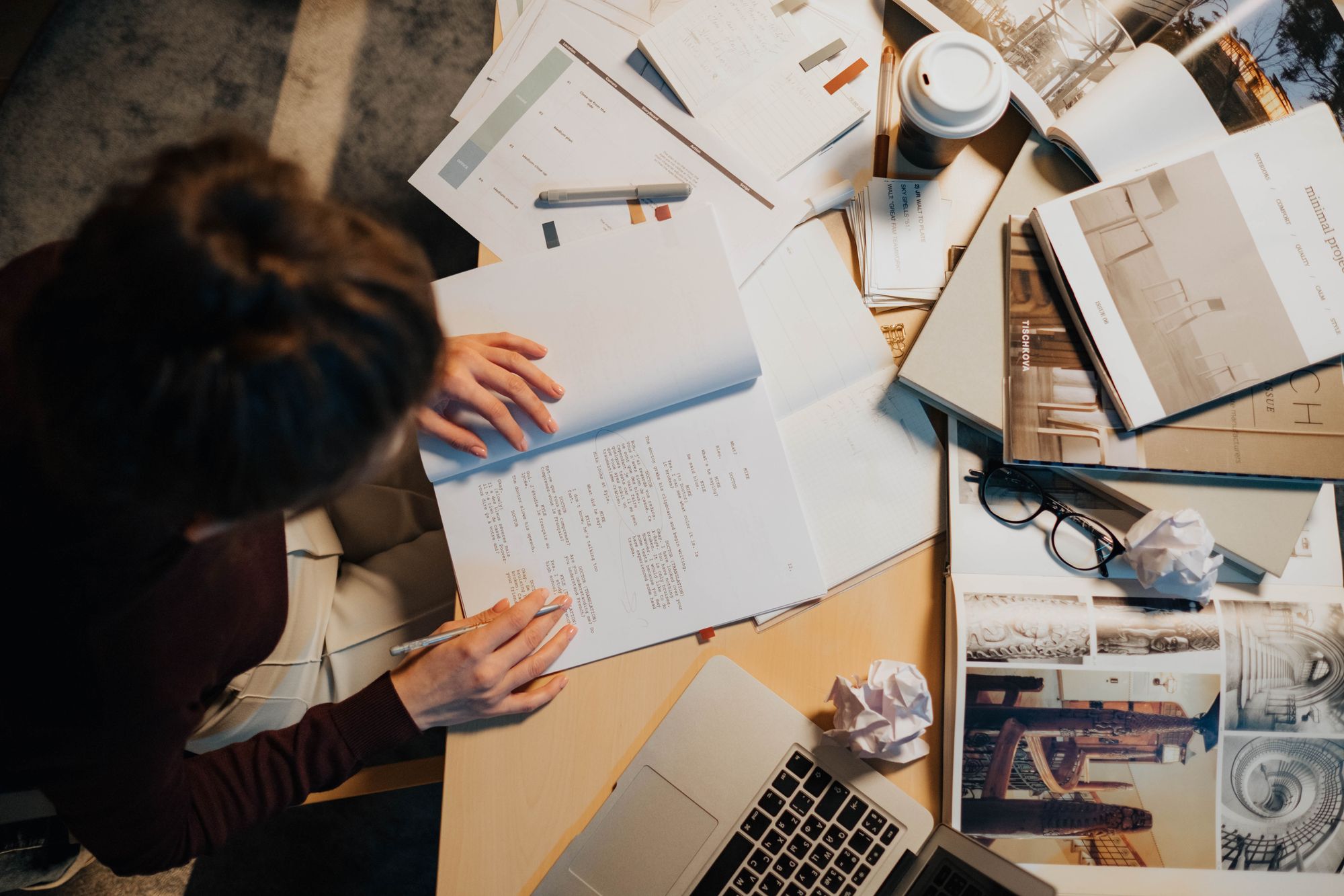 Person bei der Arbeit mit Notizen, Unterlagen und Laptop