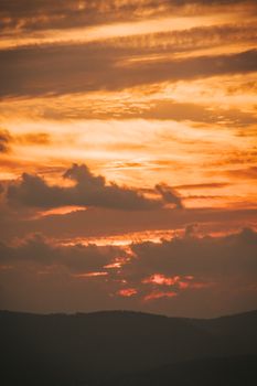 Capture of a vibrant and dramatic sunset sky with silhouetted hills, perfect for nature enthusiasts.