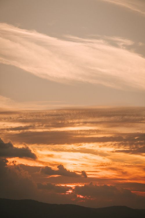 Free A striking sunset with layered clouds creating a dramatic sky, ideal for backgrounds. Stock Photo