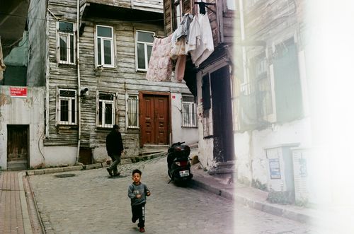 Free A young boy runs on a cobblestone street in a historic residential area of Istanbul, Türkiye. Stock Photo