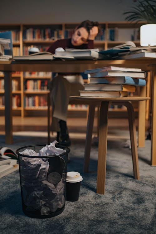 Woman Sitting at the Table in a Library and Studying 