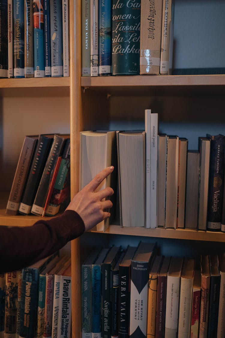 Photo Of A Person's Hand Getting A Book