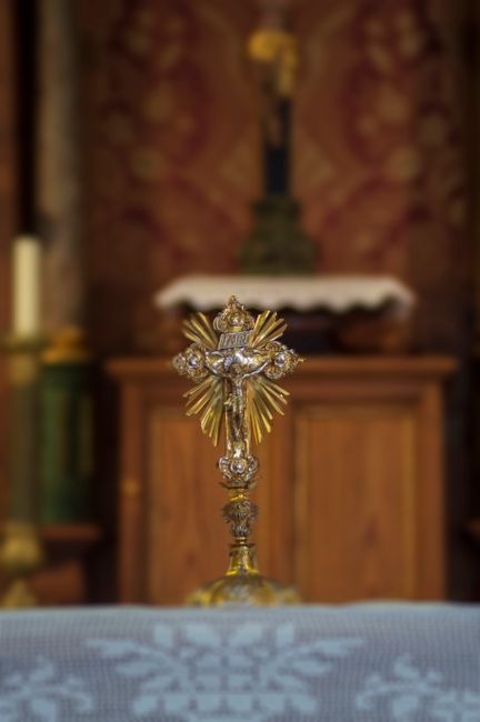 Fotomural Una vista detallada de un crucifijo dorado dentro de una iglesia, simbolizando fe y espiritualidad.