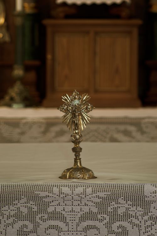 Free Close-up of a detailed gold crucifix on a lace-covered altar inside a church. Stock Photo