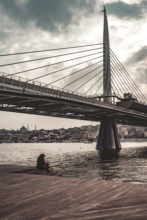 Free A serene sunset view of the Golden Horn Metro Bridge in Istanbul with a fisherman by the water. Stock Photo