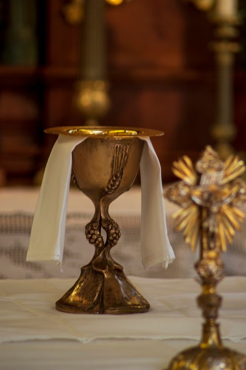 Free An ornate gold chalice with white linens displayed on an altar, symbolizing Catholic rituals. Stock Photo
