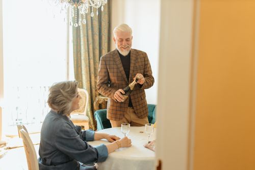 Free Elderly couple sharing a joyful moment with wine in a cozy indoor setting. Stock Photo