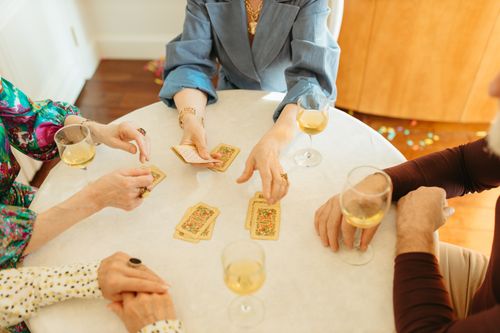 Free Adults playing cards with drinks on a table, enjoying leisure time indoors. Stock Photo