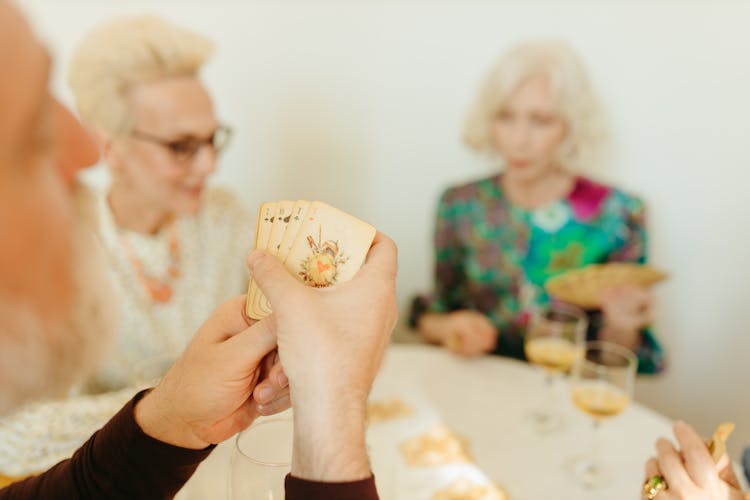 Elderly Man And Women Playing Cards