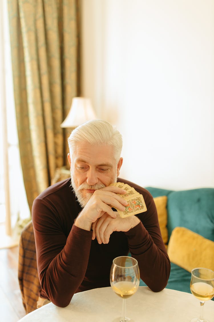 Elderly Man In Brown Long Sleeve Shirt Holding Cards