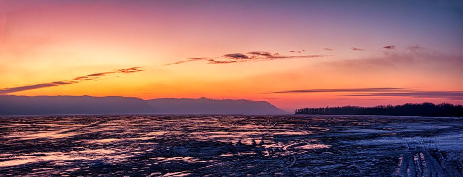 Stunning winter sunset with vibrant sky hues over a frozen Minnesota lake.