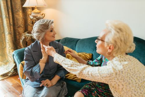 Free Two elderly women enjoy a warm and personal conversation on a comfortable couch indoors, showcasing companionship and elegant style. Stock Photo