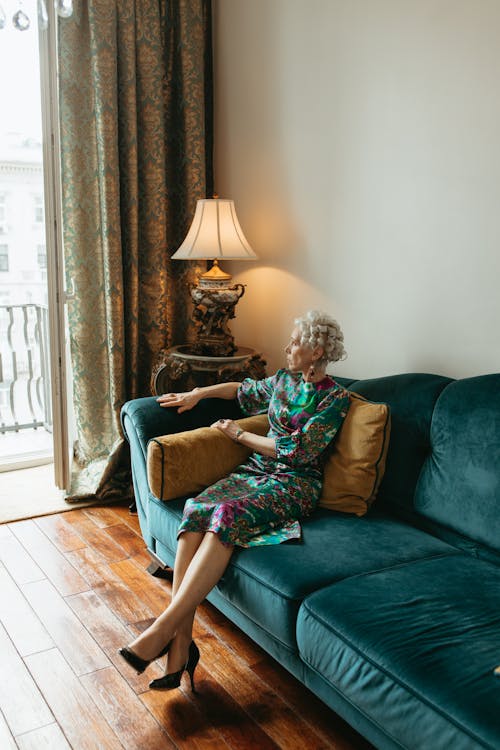Elderly Woman Sitting on a Couch While Looking Outside the Balcony